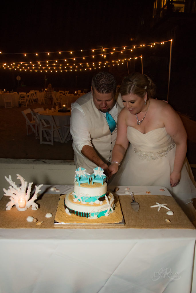 beach themed wedding cake, bride and groom cutting cake